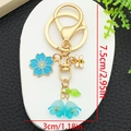 Golden keychain with blue cherry blossom, enamel bee, and gradient lily of the valley - Blue Cherry Blossom Lily Bee