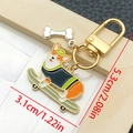 Llavero esmaltado de corgi en monopatín con colgante de hueso y cierre dorado de metal - Perro en Patineta Amarillo y Blanco (LS356)