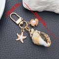 Dettaglio dei ciondoli a conchiglia, stella marina e perla su portachiavi dorato - Beige Conchiglia Stella Marina Perla Gancio a U (ER2084)