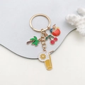 Détail de breloques en émail coloré avec cocotier et cerise sur un porte-clés doré - Style Jus Simulé (ER592)
