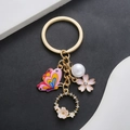 Portachiavi con farfalla rosa perla e fiore di ciliegio su anello in metallo oro - Farfalla Fiore Traforata Rosa