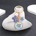 Detalle de llavero dorado con mariposa azul, perla y colgante de Happy Mother's Day - Esmalte Azul (ER701)