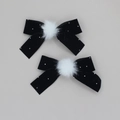 Close-up of velvet bow hair clips with rhinestones and white faux fur pom poms - Black