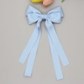 Détail d'une pince à cheveux avec ruban bleu clair et longs pans sur fond gris - Bleu Or