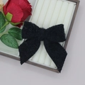 Detail einer schwarzen Plüsch-Schleife Haarspange mit Struktur auf Holztablett - Schwarz