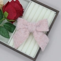 Nahaufnahme einer weichen rosa Plüsch-Schleife mit Kunstfell auf einem Holztablett - Hellrosa
