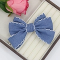 Detail view of denim bow hair clip with white scalloped embroidery on a jewelry box - Blue Scalloped Style (01#)