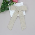 Detailansicht der beigen Plüsch-Haarschleife mit langen Bändern auf weichem Stoff - Beige