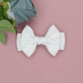 Detail einer weißen Schleife aus Satin auf einem dekorativen rosa Hintergrund für Haare - Weiß