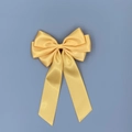 Detailed top view of a large yellow satin ribbon bow hair clip on a blue background - Gold