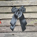 Vue détaillée d'un nœud papillon en satin noir avec de longs rubans sur un fond en bois - Noir 030