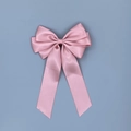Détail d'une barrette à double nœud en satin rose avec longs rubans sur fond bleu - Rose Lotus