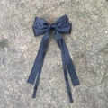 Détail d'un nœud papillon en satin bleu marine avec de longs rubans fluides sur pierre - Noir