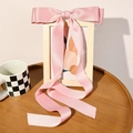 Detailansicht der langen rosa Satin-Schleife, elegant über einem Holzrahmen drapiert - Rosa