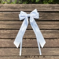 Detail of light blue satin hair bow with long ribbons on a dark wood background - Blue Gold
