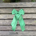 Détail d'un grand nœud papillon géant en satin vert avec rubans sur fond en bois sombre - Vert 587