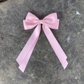 Pink satin ribbon hair bow with long streamers on a textured grey stone surface - Pink