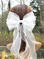 Detail of multi-layer white organza ribbon bow hairclip on model in natural lighting - White