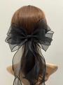 Dettaglio di un grande fermaglio per capelli in organza nera con lunghi nastri - Nero