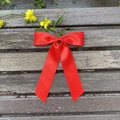 Detail of red oversized satin bow hair clip with long ribbons on rustic wood background - Red