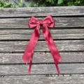 Detail of burgundy large ribbon hair clip with elegant long streamers on wood - Burgundy