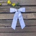 Detail einer weißen Satin-Schleife Haarspange mit langen Bändern auf Holzgrund - Weiß