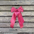 Détail d'un grand nœud papillon en satin bordeaux avec de longs rubans sur du bois - Bordeaux 275