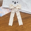 Close-up of beige ruffled ribbon bow hair clip with long streamers and wavy edges - Khaki