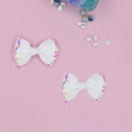 Close-up of white grosgrain ribbon hair bows with colorful confetti on pink background - White