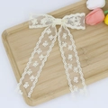 Détail d'une pince à cheveux avec nœud en dentelle blanc crème et broderie florale - Beige