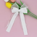 Detail einer weißen geschichteten Organza-Schleife-Haarspange mit fließenden Bändern - Weiß