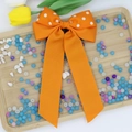 Dettaglio del fiocco per capelli arancione a pois in grosgrain con lunghi nastri - Arancione