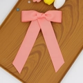 Détail du nœud papillon en ruban rose avec de longs rubans sur un plateau en bois - Rose Pastèque