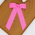 Détail d'un nœud papillon rose vif en ruban gros-grain avec rubans sur un plateau en bois - Rose foncé