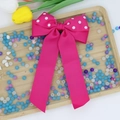Dettaglio di un grande fiocco in gros-grain fucsia a pois con lunghe code fluenti in seta - Rosso rosa