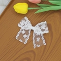 Détail d'une pince à cheveux avec nœud en dentelle blanche et motifs floraux ajourés - Blanc
