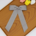 Détail d'un nœud papillon gris en tissu côtelé avec rubans sur un plateau en bois - Gris