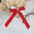 Detailed close-up of a dual-layer red and white satin ribbon bow hair clip on fur - Red + White