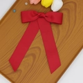 Détail d'une pince à cheveux avec nœud en gros-grain rouge et longs rubans sur bois - Rouge