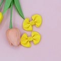 Detail of two bright yellow ribbed grosgrain bow hair clips on pink background - Yellow