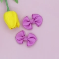 Detail of two purple ribbed ribbon hair bow clips on a soft pink background with a tulip - Purple