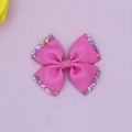 Macro detail van roze grosgrain strik haarspeld met kleurrijke suiker sprinkles op de randen - Dieproze