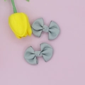 Close-up of grey ribbed texture bow hair clips set with yellow tulip on pink background - Gray