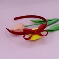 Detail shot of a deep red grosgrain ribbon bow headband on a pink floral background - Red