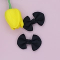 Detail view of a pair of black grosgrain ribbon bow hair clips on pink background - Black