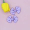 Detail view of two sweet lavender grosgrain ribbon bow hair clips on a soft pastel background - Lavender
