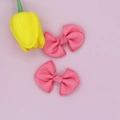 Close-up detail of two pink ribbed grosgrain ribbon hair bow clips with textured finish - Pink