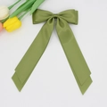 Détail d'un nœud papillon en satin vert herbe avec de longs rubans et un fini soyeux - Vert Militaire