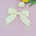 Elegant cream lace bow hair clip with satin fabric on a soft pink floral background - Off White