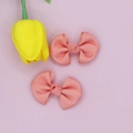 Macro detail of two pink ribbed grosgrain bow hair clips on a soft minimalist background - Pink